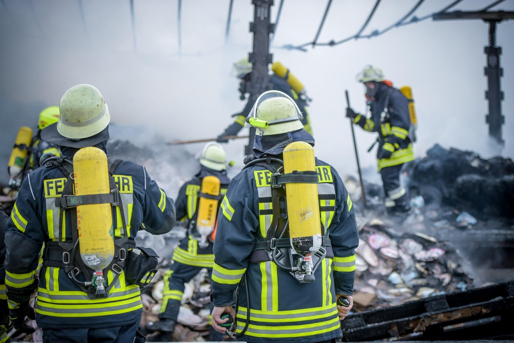 Firefighters inspecting a burned passenger boat for remaining hot spots after fire suppression