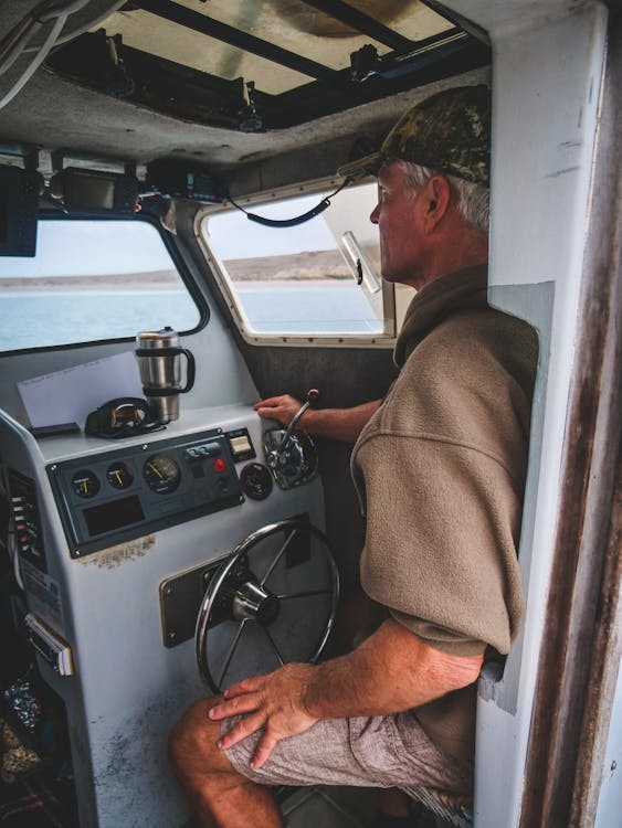 a man sitting in front of the boats wheel