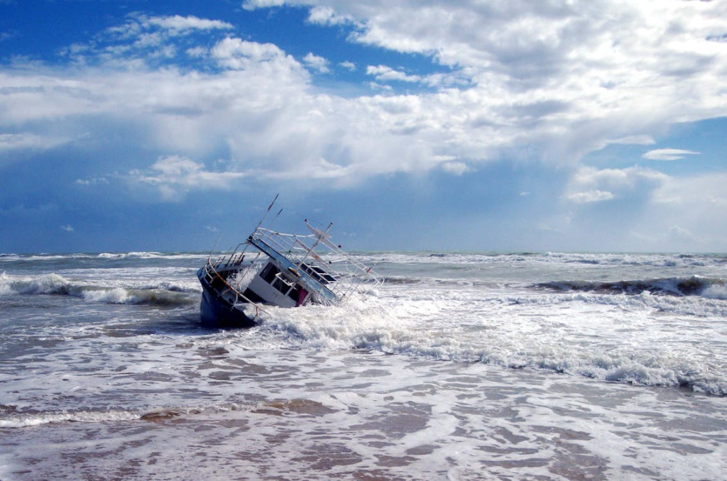a boat on the seashore with waves crashing on it